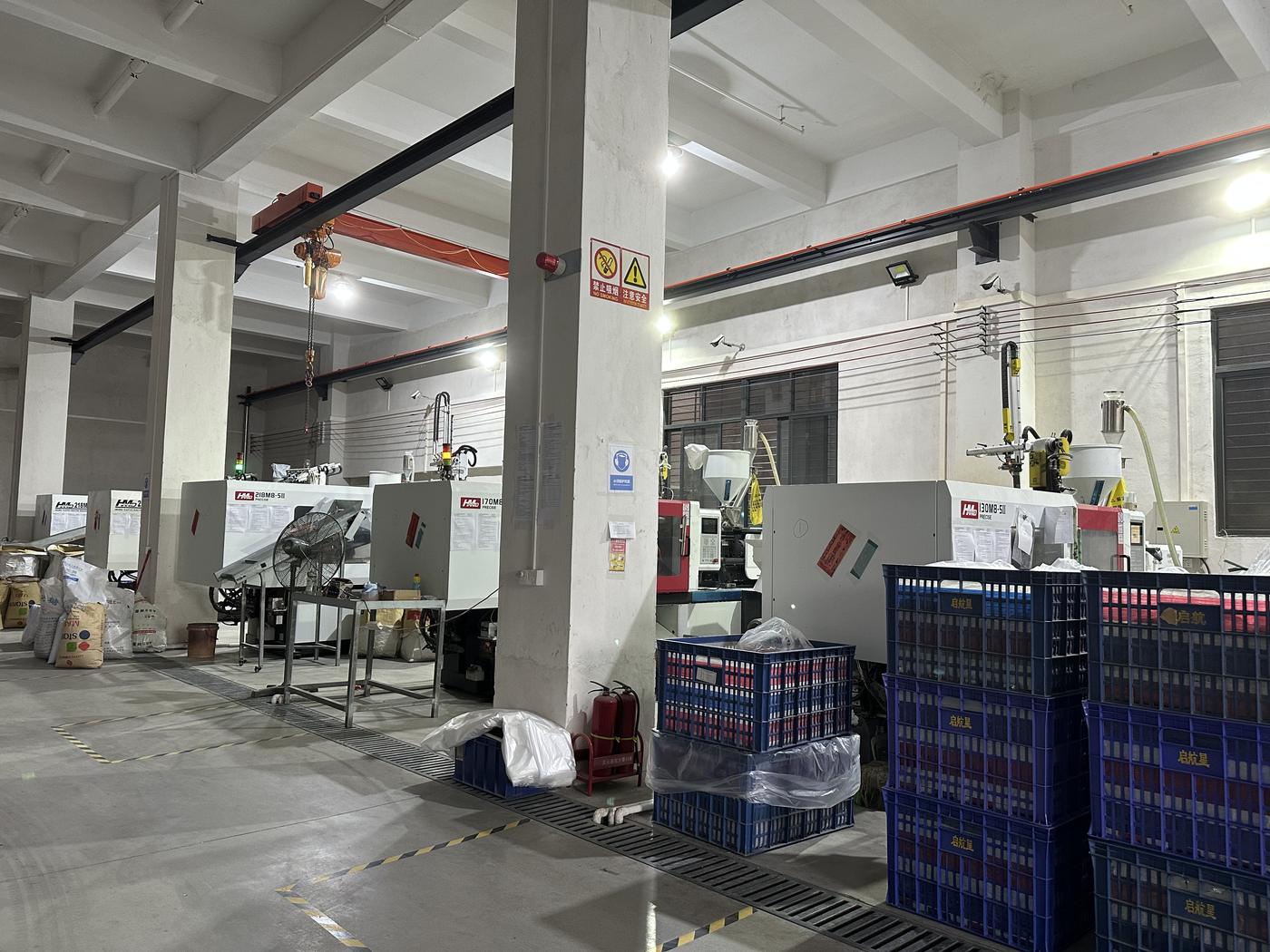 Toy factory floor with injection molding machines and material crates